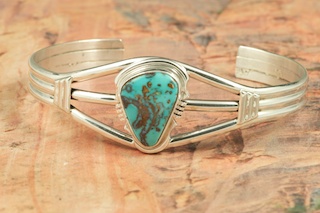 Genuine Royston Turquoise set in Sterling Silver Bracelet. The Royston Turquoise Mine was originally known as the Royal Blue Mine. It produces Turquoise that has a mixture of blues and greens in the same formation. The Royston Turquoise Mine is located in Nye County, Nevada. Created by Navajo Artist Arkie Nelson. Signed by the artist.